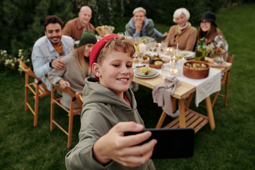 Cheerful family taking a selfie during an outdoor garden dinner party.