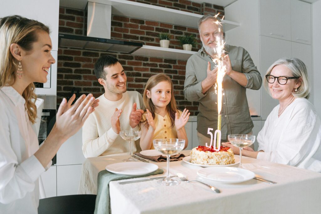 Joyful family gathering around a cake celebrating a 50th birthday indoors.