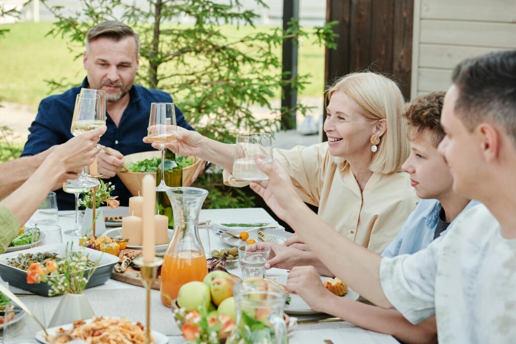 Family enjoying a meal outdoors, toasting with wine, showcasing togetherness and celebration.